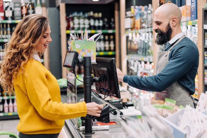 A woman pays for her groceries at the cash register using a credit card.