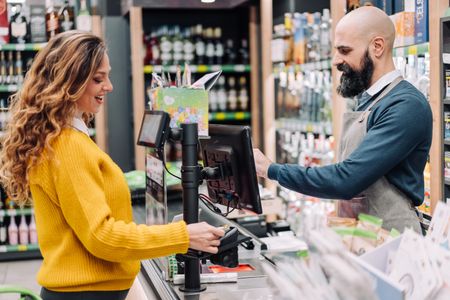 A woman pays for her groceries at the cash register using a credit card.