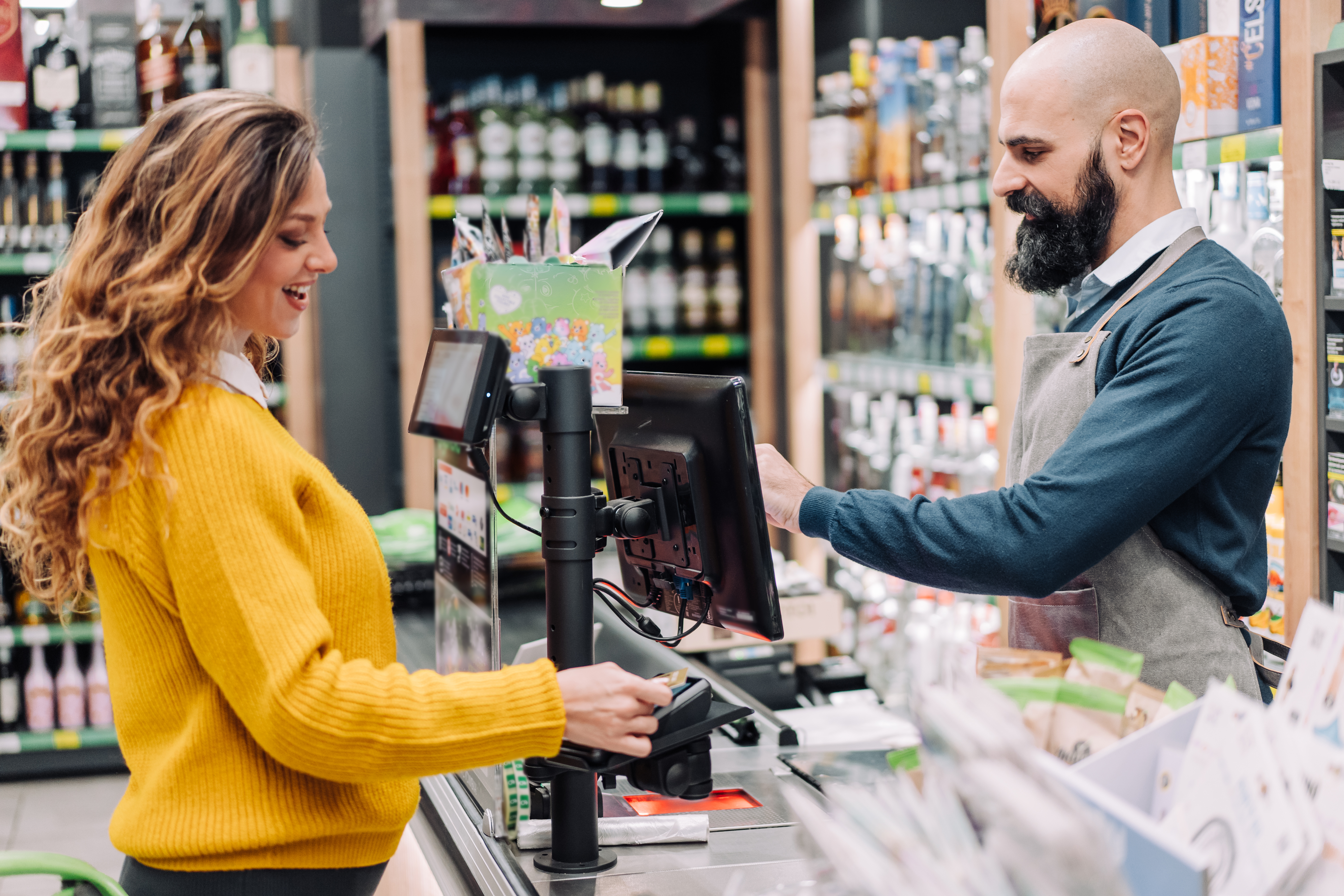 A woman pays for her groceries at the cash register using a credit card.