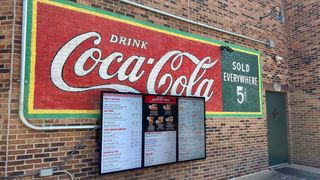 A new digital menu in front of a classic Coca Cola sign from Palmer Digital Media. 