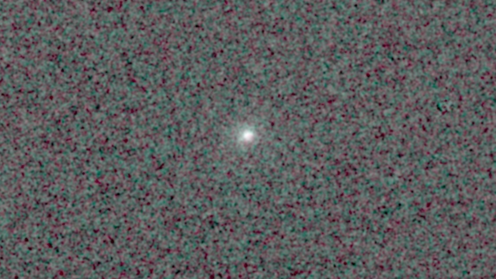 Comet 3I/ATLAS is feasible as a bright point of glowing light in the center of a pixelated black and dark grey background.