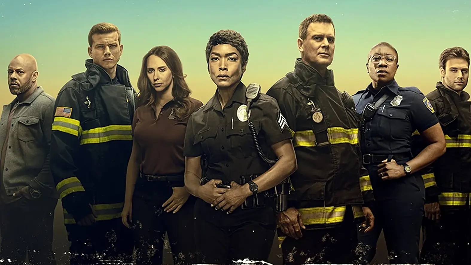 9-1-1 promotional group shot. The cast stand in a line posing for the camera in their uniforms.