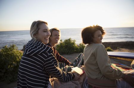 Smiling young friends hanging out on sunset beach