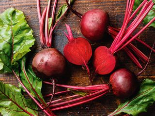 fresh beetroot on a wooden chopping board with several pieces cut in half