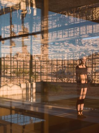 Image of a naked woman standing in a building with rocky background