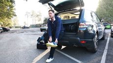 Golfer changing shoes in car park