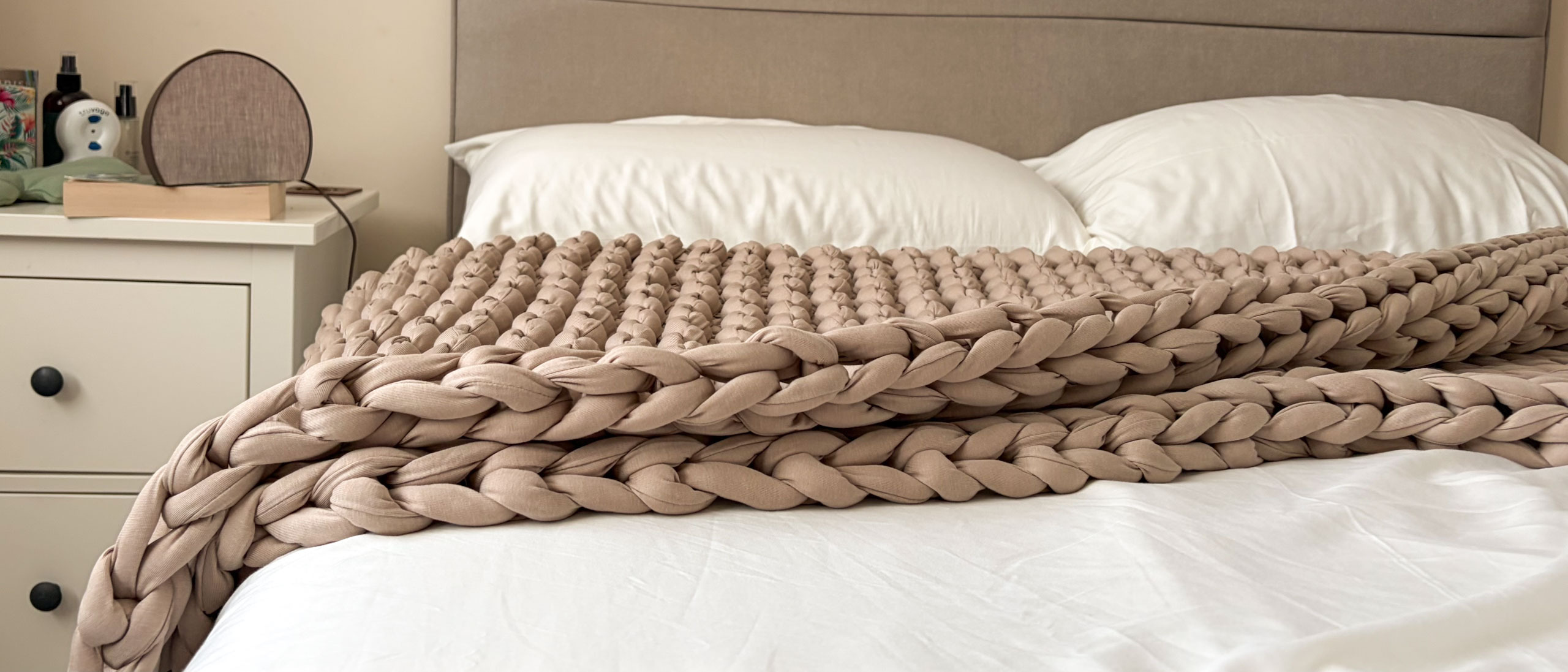 The Bearaby Tree Napper weighted blanket draped across the bed in our reviewer's bedroom