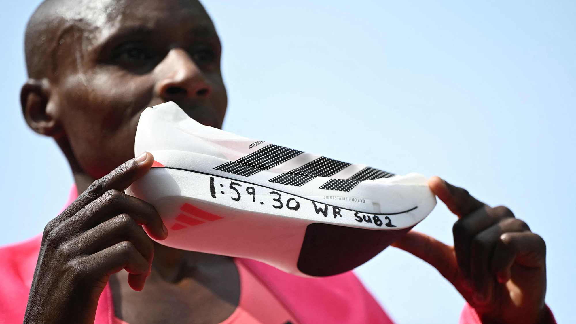 Kenya's Sabastian Sawe poses with his new world record time written on his running shoe at the finish of the 2026 London Marathon, breaking the two-hour mark for the first time in history