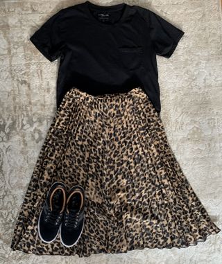 A black t-shirt, animal print skirt, and black sneakers.