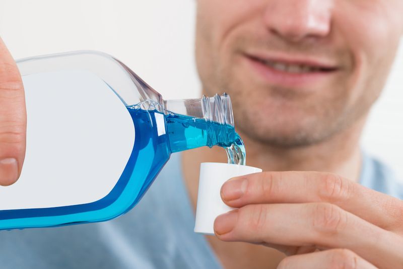 A man pours some mouthwash from a bottle