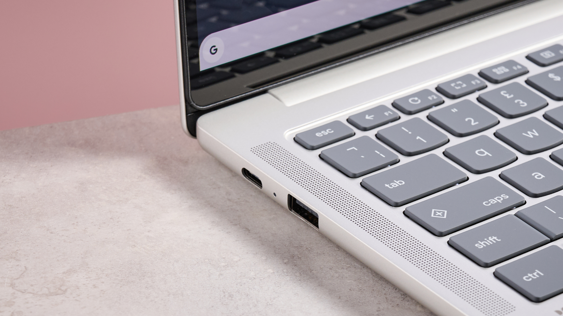 Close-up of left-hand ports on Lenovo Chromebook Plus 14-inch, on desk with pink background
