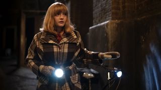 Natalie Quarry as Rosalind in a check coat holds a torch as she walks down a street in the Call the Midwife Christmas Special 2024.