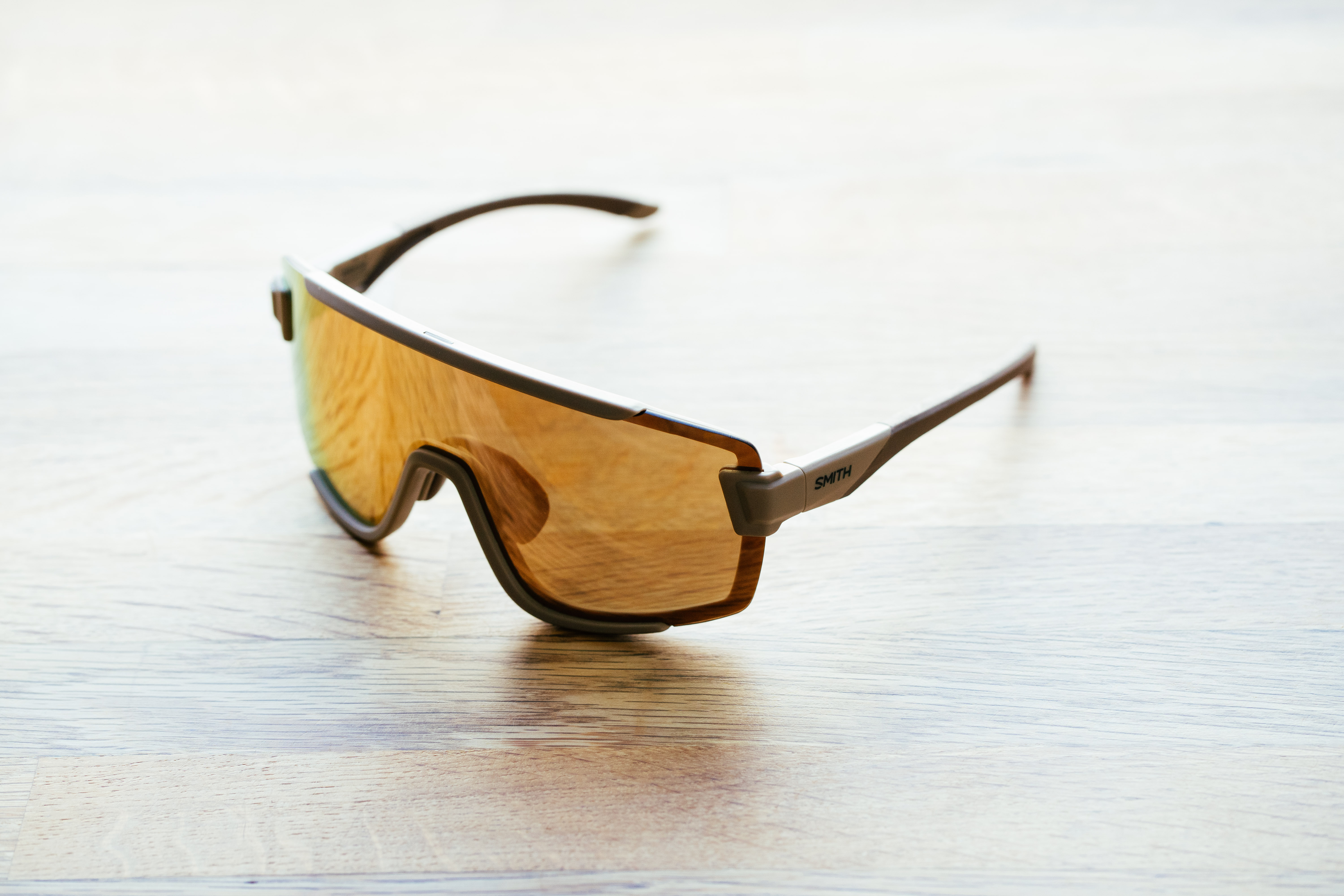 A gold pair of sports glasses on a wooden surface