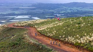 Riders on the final stage of the 2023 Cape Epic, climbing and being followed by a helicopter