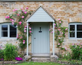 stone cottage with pink roses around the door
