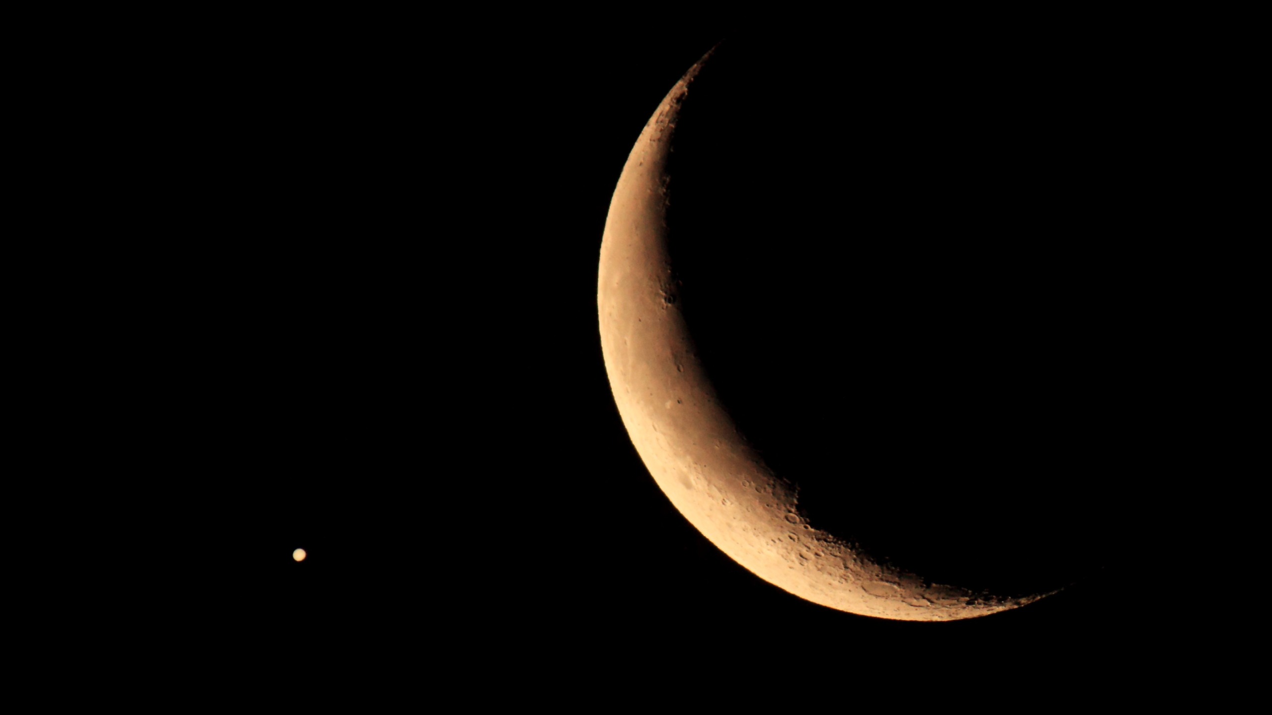a thin crescent moon on the right and a bright point of light on the left - this is Jupiter