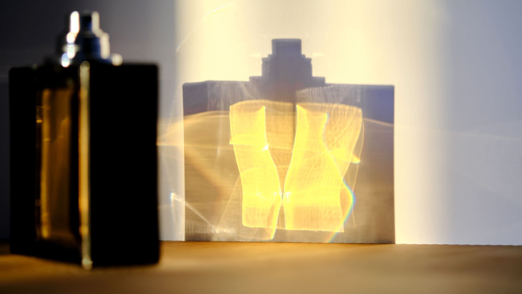 a bottle of fragrance and its reflection against a white wall - k-fragrance