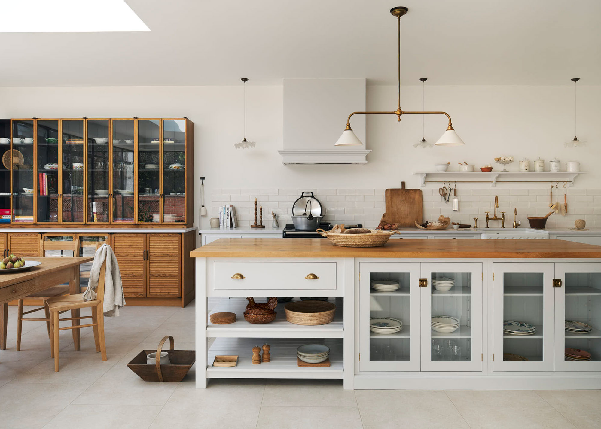 white kitchen with large island that has glass fronted cabinets.