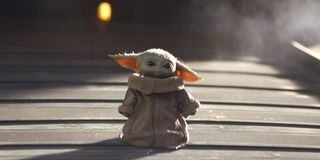 Baby Yoda standing by himself looking sad.
