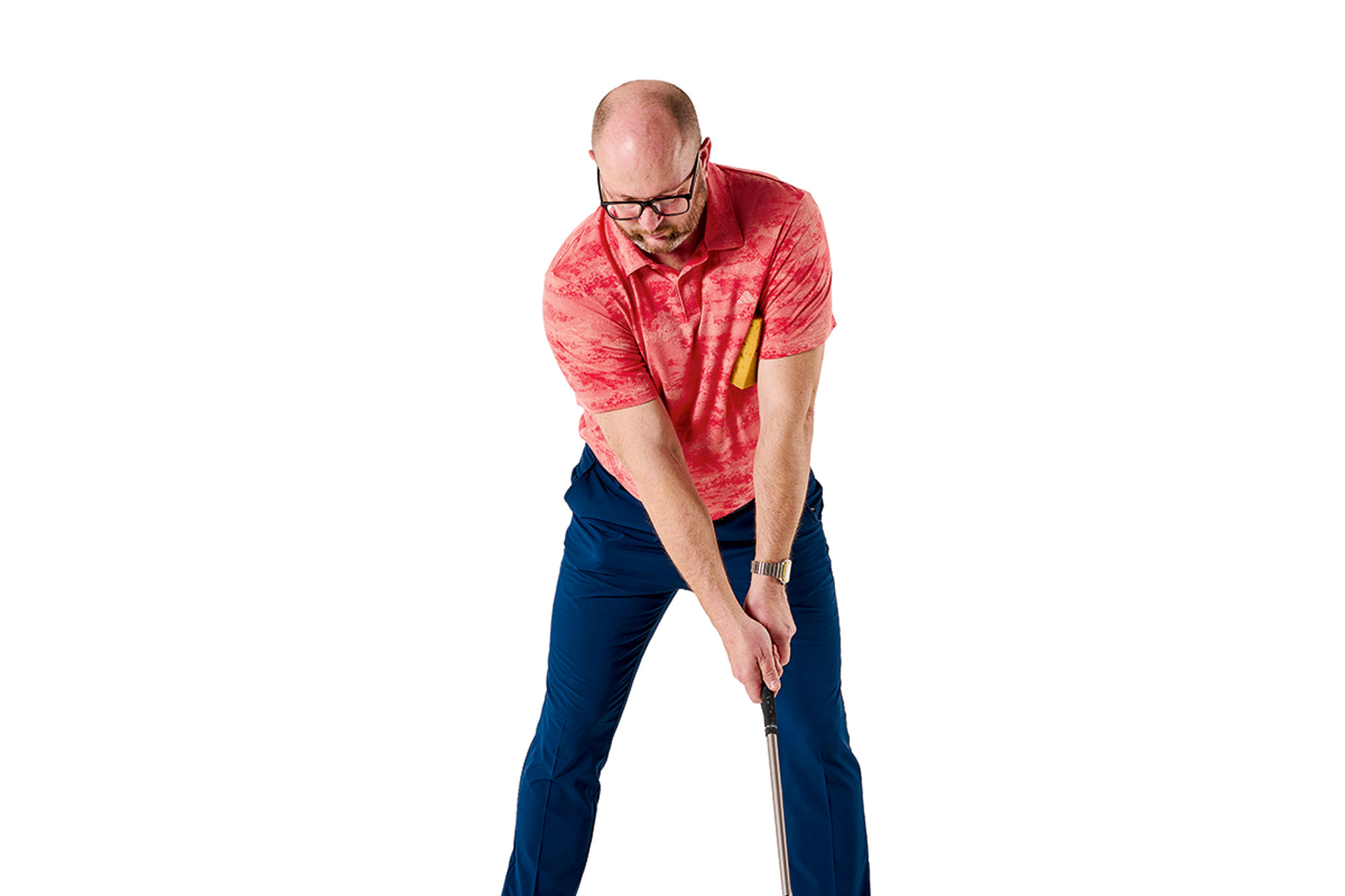 Russell Covey demonstrating how to do the sponge drill, with the sponge tucked under his lead arm as he addresses the golf ball