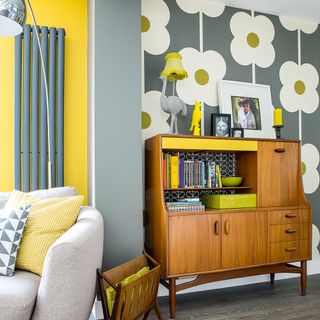 Living room with retro printed wallpaper and mid-century bureau