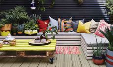 colourful painted seating area on a decked patio with a yellow pallet coffee table and colourful outdoor cushions