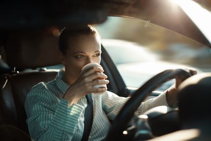 Woman driving a car and drinking from a coffee cup