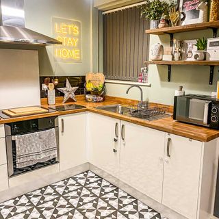 kitchen with white cabinet wooden counter wooden shelf and designed floor