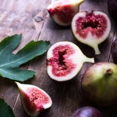 Sliced figs and fig leaf on a wooden table