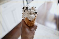 A close up of a person holding a cone of Oreo ice cream