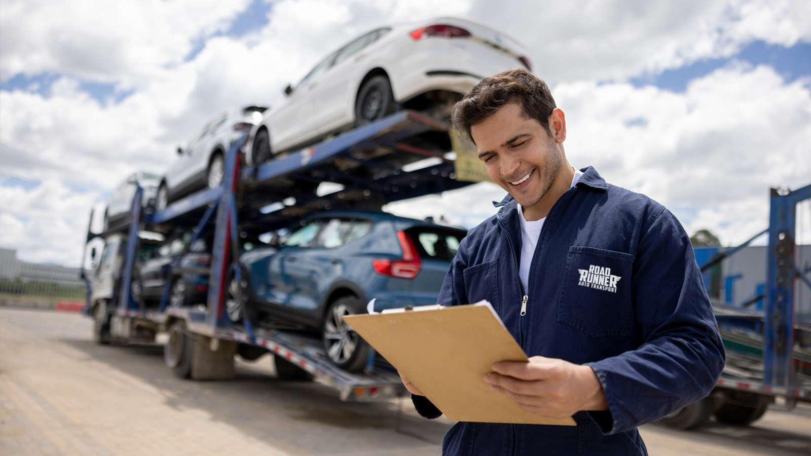 A RoadRunner employee checking a clipboard with a truck behind them.