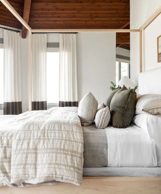 Wooden beamed room with a White and brown striped duvet on top of a neutral bed