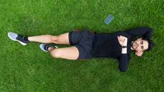 Runner lying on grass checking his GPS watch