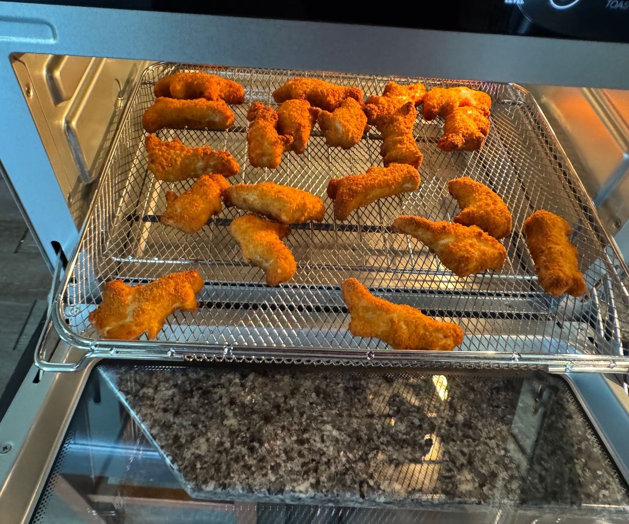Chicken nuggets arranged on a wire mesh tray in the Typhur Sync Air Fryer Oven