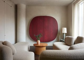 Living room with curved column, off-white limewash walls, red canvas wall painting and beige boucle sofas