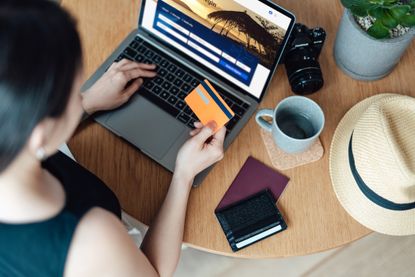 High angle view of young woman booking flight tickets online using laptop.