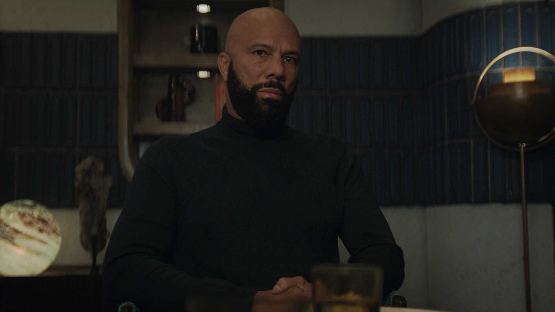 a bearded man sits calmly in a dark room