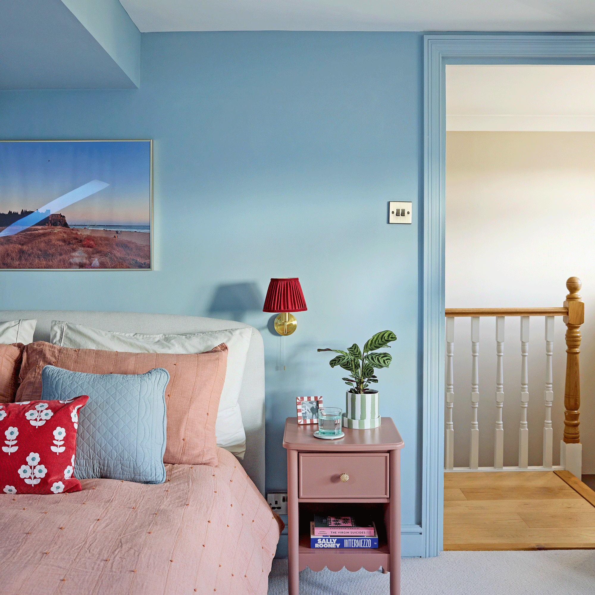 a blue and pink bedroom with pops of red with colourful accesories