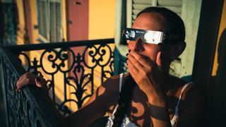 Illustrative photo of a young woman sitting on the balcony of her flat in Nice's Old Port, wearing protective glasses for the solar eclipse scheduled for 12 August 2026