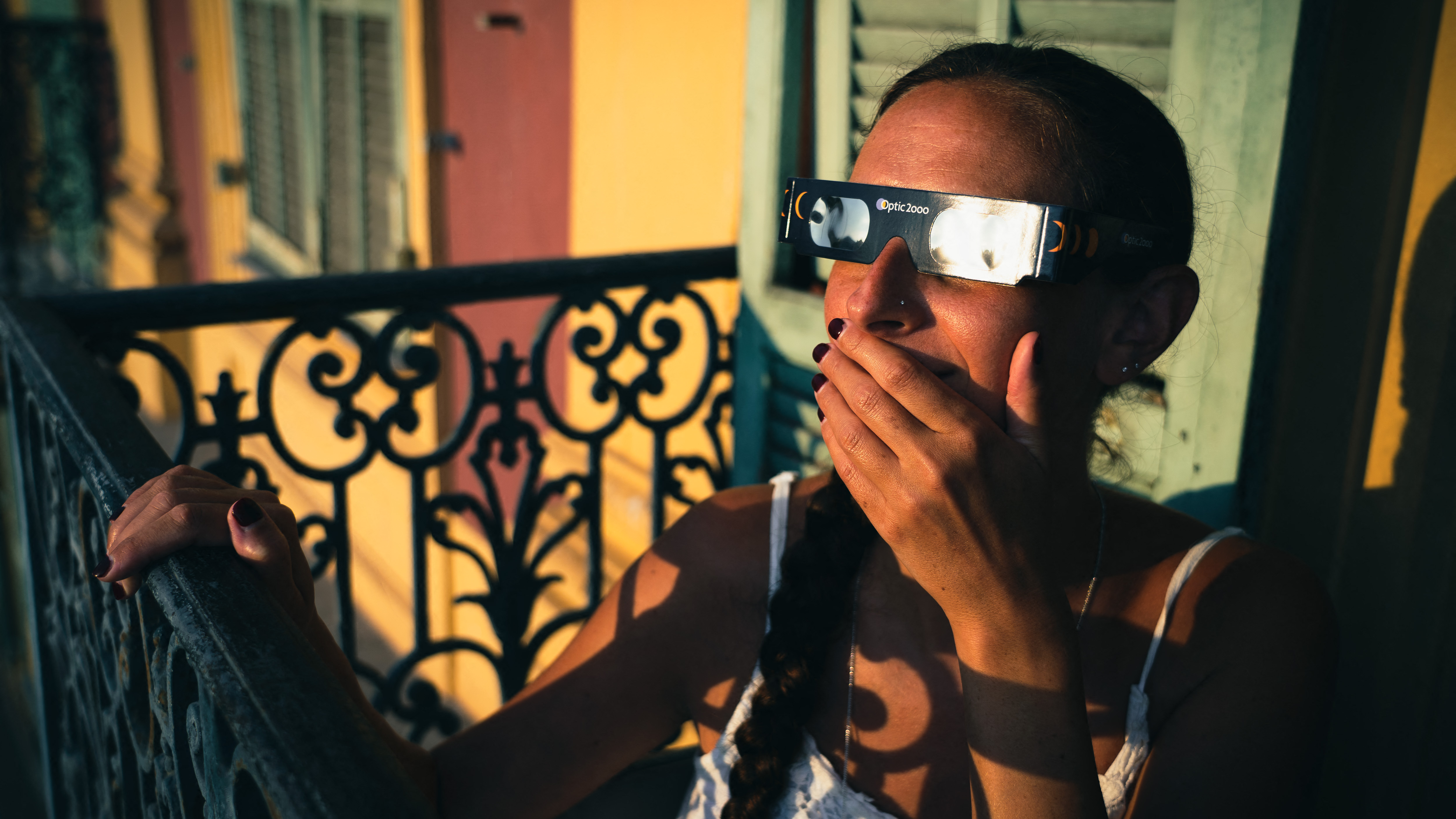 Illustrative photo of a young woman sitting on the balcony of her flat in Nice's Old Port, wearing protective glasses for the solar eclipse scheduled for 12 August 2026