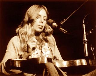 an older photo of joni mitchell performing live in the '70s