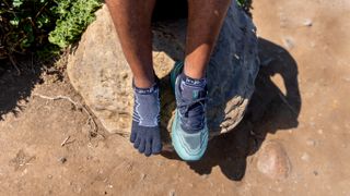 A runner's feet with one shoe off revealing they are wearing Ininji toe socks