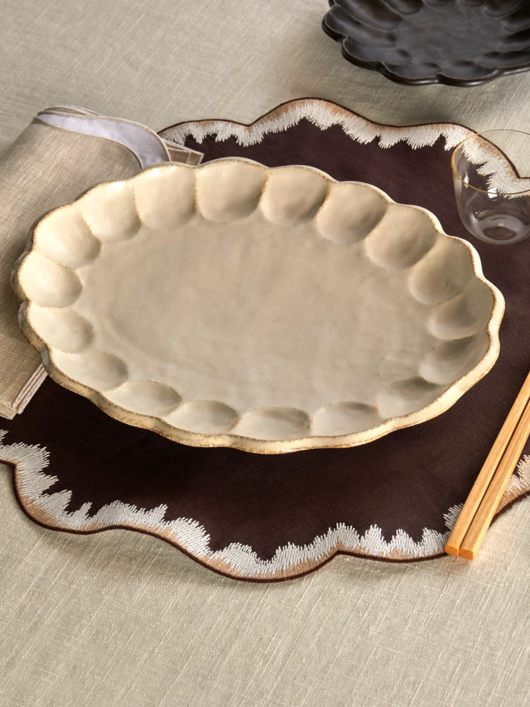 A ceramic oval dinner plate with a scallop indent border from Kaneka Kohyo