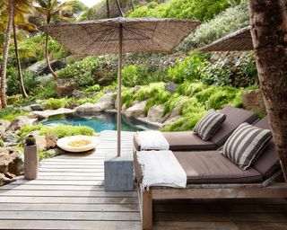 natural pool amongst rockery with sun loungers and parasol