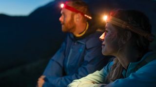 Man and woman wearing BioLite HeadLamp 330 headlamps at night
