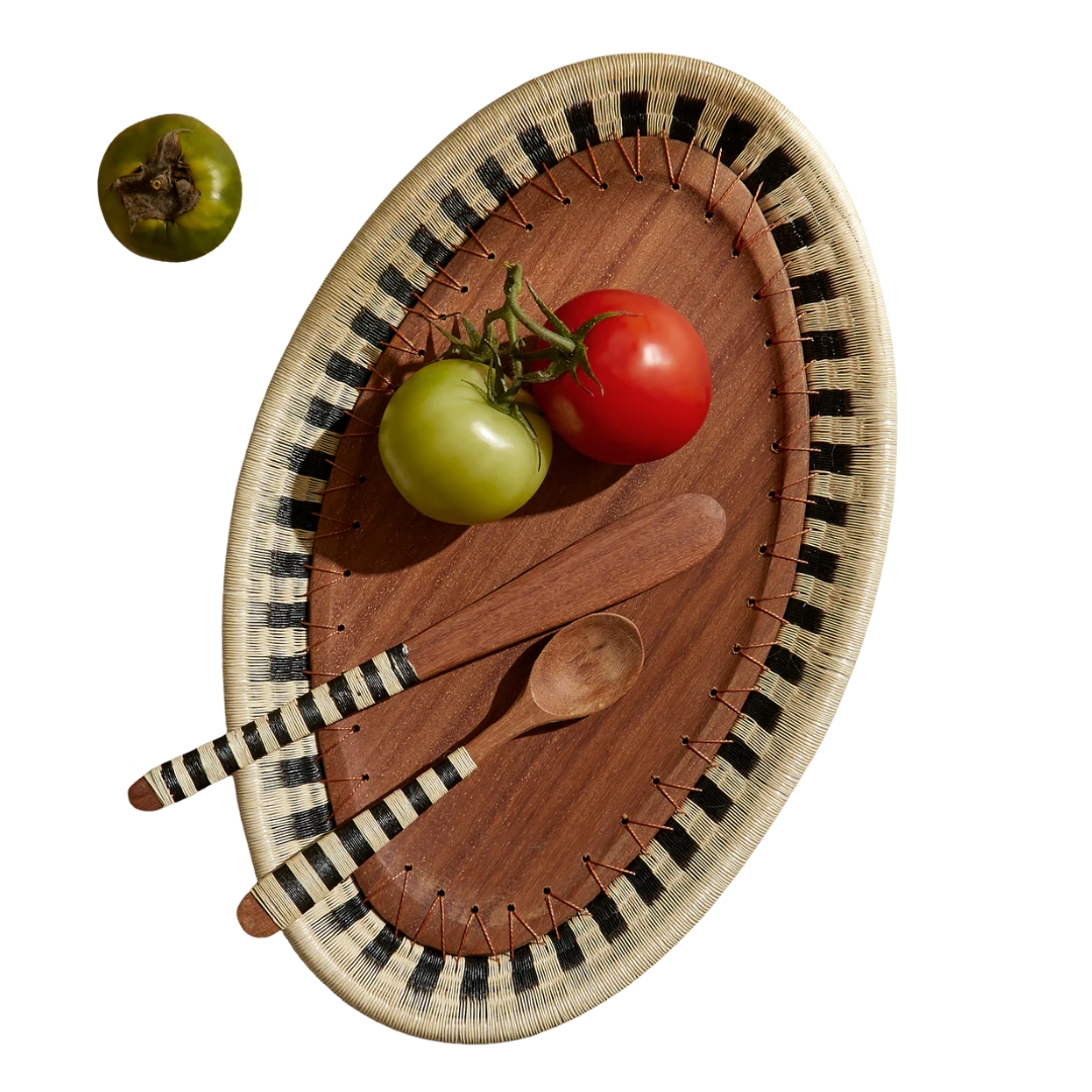 A wood and textile handwoven dish filled with tomatoes and patching cutlery bearing the same striped motif.