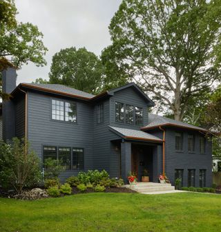 gray house with shiplap facade with steel framed windows and lawn with mature trees