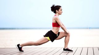 woman stretching into a lunge on a boardwalk