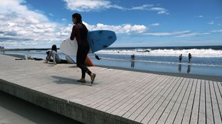 surfer walking on the boardwalk near rockaway beach in NY