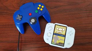 MagicX Zero 40 handheld in white next to blue Nintendo 64 controller on woodgrain desk.
